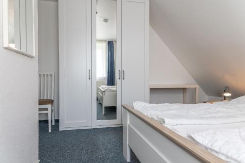 um quarto branco com uma cama e um espelho em Ferienhaus 50009 em Carolinensiel