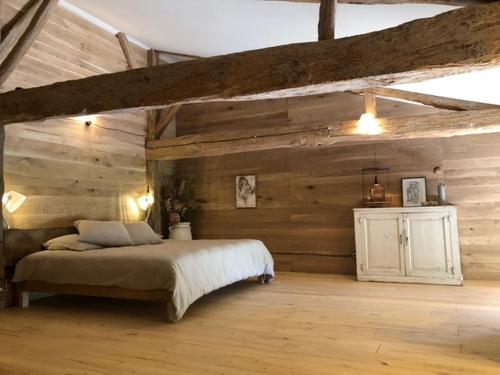 une chambre avec un lit et un mur en bois dans l'établissement Maison Drôles d'Oiseaux, à Plieux
