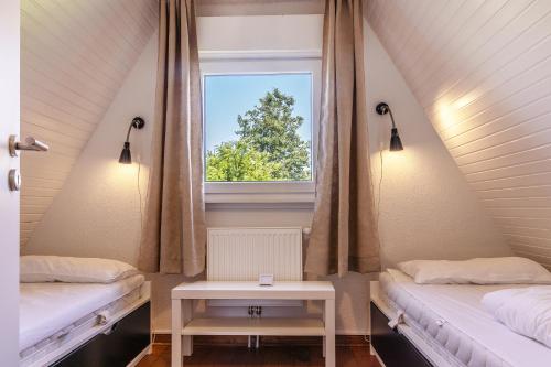 a attic room with two beds and a window at 50171 Haus Antje I in Harlesiel