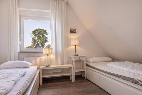 two beds in a room with a window at 50172 Haus Antje II in Harlesiel