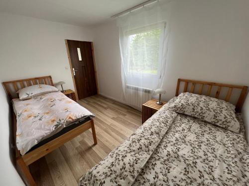 a bedroom with two beds and a window at Wagończyk in Grzegrzółki