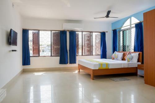 a bedroom with a bed and some blue curtains at OYO Home Elite Stay Near Shri Shri Shiridi Sai Mandir in Khandagiri
