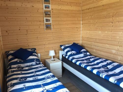 two beds in a room with wooden walls at Domki Wypoczynkowe "Sea Breeze" in Rewal