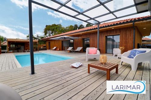 une terrasse en bois avec une piscine et une maison dans l'établissement Larimar, à Léon