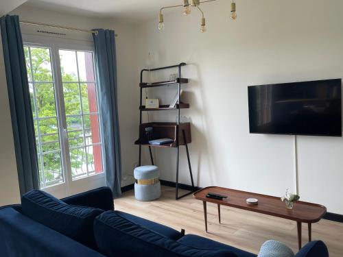 a living room with a blue couch and a tv at Ambiance Seine, appartement surplombant la Seine -51 M2, Anémone- in Thomery
