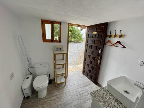 a bathroom with a toilet and a sink and a door at Boutique Teepee Sleeps 2 with Pool in Zújar