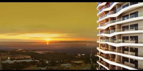 a view of a building with the sunset in the background at Coast Residences Penthouse with skyline and manila bay view in Manila