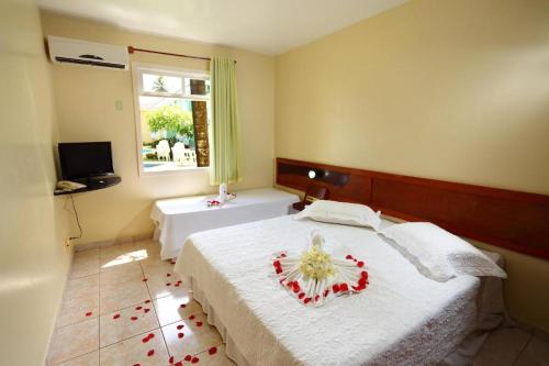 a bedroom with a bed with a flower arrangement on it at Apart Hotel Boulevard da Praia - Portal Hotéis in Porto Seguro