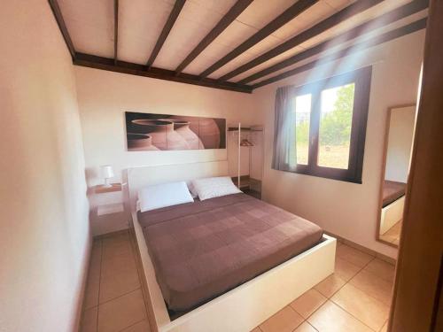 1 dormitorio con 1 cama grande y ventana en Casetta Madre Vita, en Belvedere