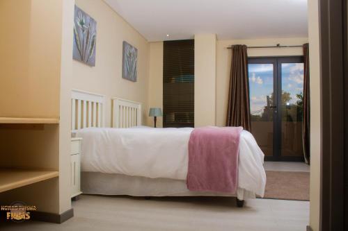 Staybridge Golfview Suites في غابورون: غرفة نوم بسرير وملاءات بيضاء ونافذة