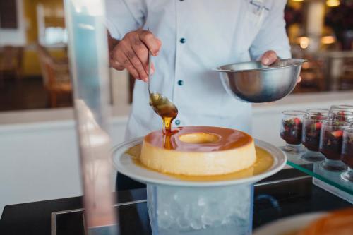 a chef drizzling sauce on a cake on a plate at Transamerica Comandatuba - All Inclusive Resort in Ilha de Comandatuba
