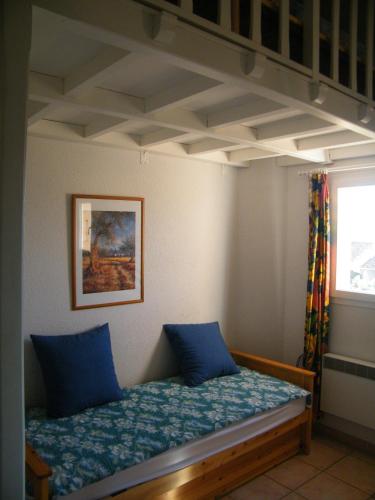 une chambre avec un lit avec des oreillers bleus dessus dans l'établissement Coquet Pavillon classé meublé de tourisme Narbonne Plage, à Narbonne-Plage