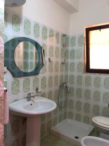 a bathroom with a sink and a toilet and a mirror at Villa Edi in Vlorë