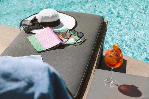 a hat and glasses sitting on a table next to a pool at Glyfada Riviera Hotel in Athens