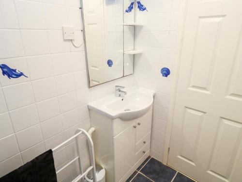 uma casa de banho branca com um lavatório e um espelho em 16 Seaspray em Truro