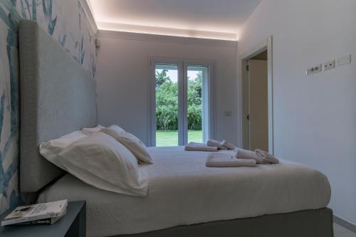 a bedroom with a bed with white sheets and a window at Villa Golden Root Real Estate in San Teodoro