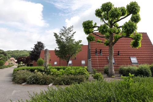 a red house with a tree in front of it at Vakantie bij Meeussen - Molendal in Plasmolen