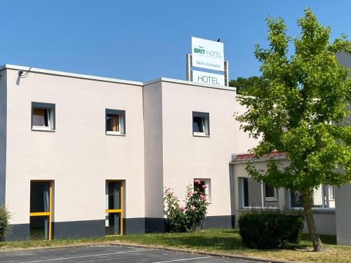 a white building with a sign on top of it at Brit Hotel Reims La Pompelle in Reims