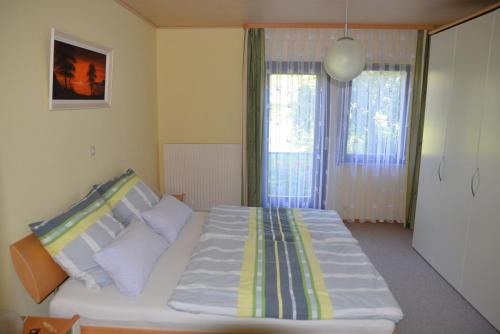 um quarto com uma grande cama branca e 2 janelas em Ferienwohnung Dürnbach em Albstadt