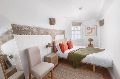a white bedroom with a bed and a chair at Newly Renovated City Apartment in Bath