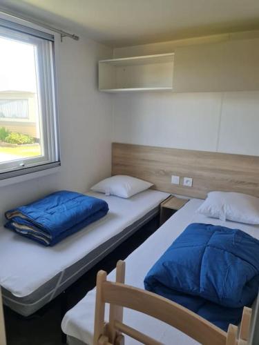 twee bedden in een kamer met een raam bij Mobil-home Magnolia 300m de la plage Ambleteuse in Ambleteuse