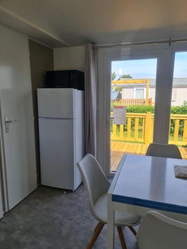 Il comprend un balcon et une cuisine équipée d'une table et d'un réfrigérateur. dans l'établissement Mobil-home Magnolia 300m de la plage Ambleteuse, à Ambleteuse