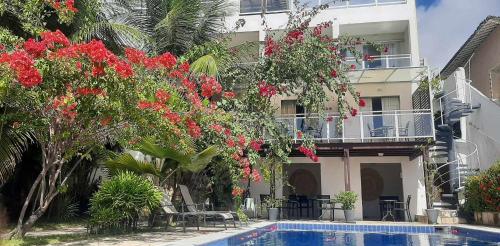 a house with red flowers and a swimming pool at Innsenso B&B in Natal