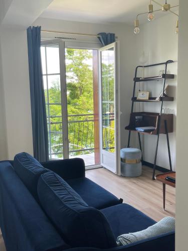 un salon avec un canapé bleu et un balcon dans l'établissement Ambiance Seine, appartement surplombant la Seine -51 M2, Anémone-, à Thomery