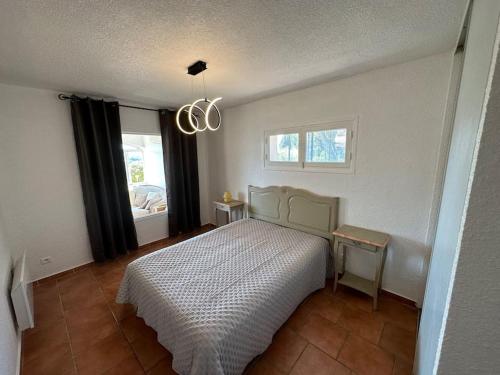 une chambre avec un lit, une fenêtre et un lustre dans l'établissement Grand T2 très lumineux en rez de jardin villa, à Carqueiranne