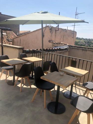 a group of tables and chairs with an umbrella on a roof at Hotel François 1Er in Manosque