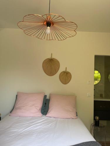 - un lit avec 2 oreillers roses et un ventilateur de plafond dans l'établissement Ambiance Seine, Appartement lumineux en bordure de Seine - Chouette, à Thomery