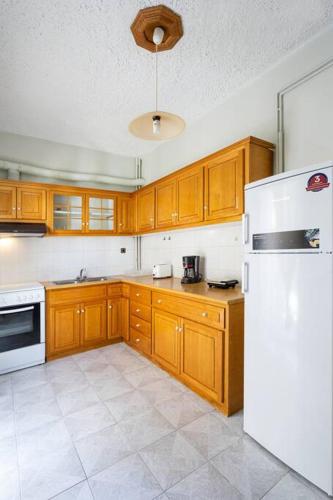 a kitchen with wooden cabinets and a white refrigerator at Cozy Apartment 2 in Sitia