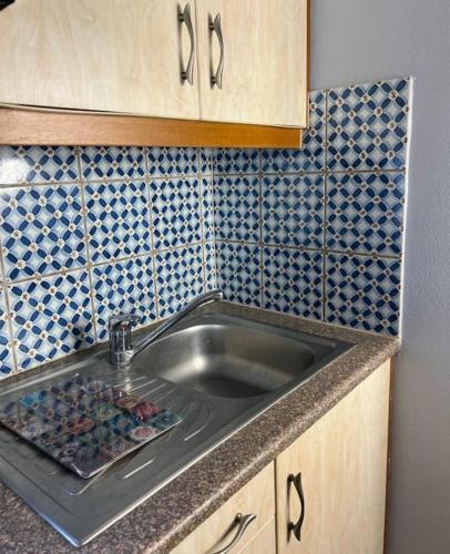 a kitchen counter with a sink and blue tiles at Pink House 2 in Palaiochora