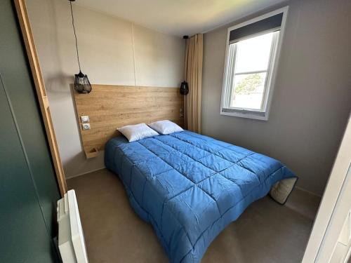 a bedroom with a blue bed with a window at O'hara mobil-home haut de gamme à 300m de la plage in Ambleteuse