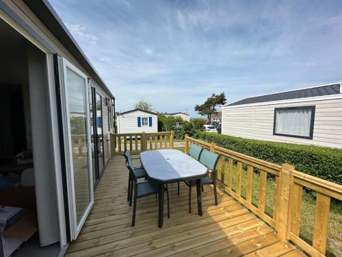 une terrasse en bois avec une table et des chaises dessus dans l'établissement O'hara mobil-home haut de gamme à 300m de la plage, à Ambleteuse