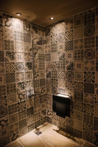 a bathroom with a shower with a tiled wall at Le Petit Chateau & William de Percy in Otterburn