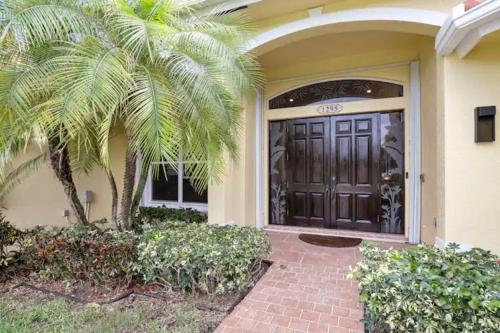 une porte d'entrée d'une maison avec un palmier dans l'établissement Singer Island Beach Oasis: Heated Pool & 2022 Renovations, à West Palm Beach