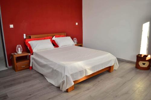 1 dormitorio con 1 cama grande y pared roja en Room in Villa - The romantic atmosphere of the red room to discover the pleasure of a stay, en Antananarivo