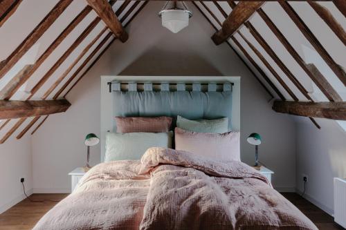 a bedroom with a bed in a attic with wooden beams at The Cotswold Farm Hideaway in Alderley