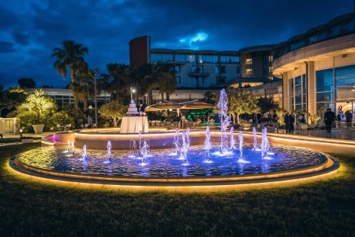 a fountain with blue lights in front of a building at UNA HOTELS MH Matera in Matera