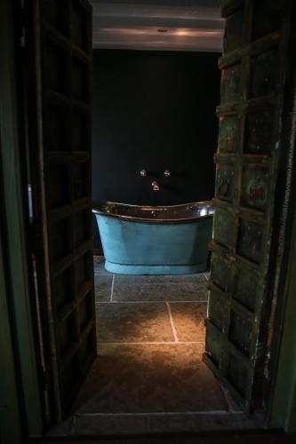 a bathroom with a blue tub in a dark room at Le Petit Chateau & William de Percy in Otterburn
