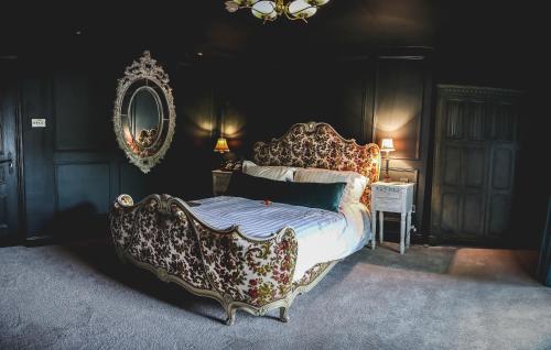 a bedroom with a king sized bed with a fancy headboard at Le Petit Chateau & William de Percy in Otterburn