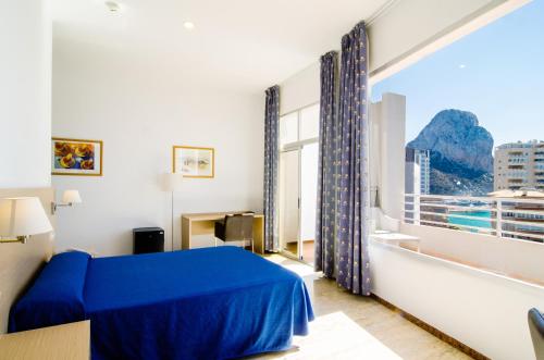 1 dormitorio con cama azul y ventana grande en Lovely Port Europa 1 Bedroom apartment 2 Adults 1 Child, en Calpe