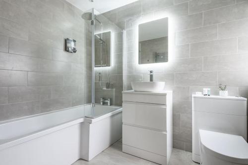 a bathroom with a sink and a tub and a toilet at Spacious, Modern Home, Central Newquay w/ parking in Newquay