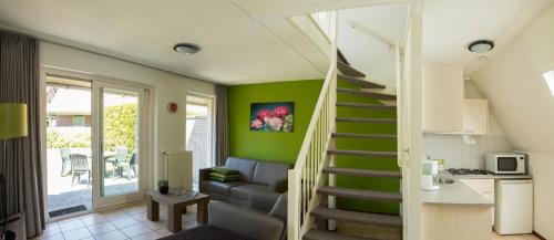 Un escalier mène à un salon aux murs verts. dans l'établissement Vakantie bij Meeussen - Molendal, à Plasmolen