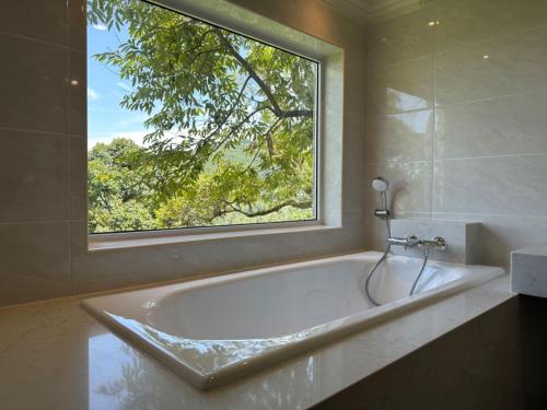 y baño con bañera y ventana. en Bao Sheng Durian Farm en Balik Pulau
