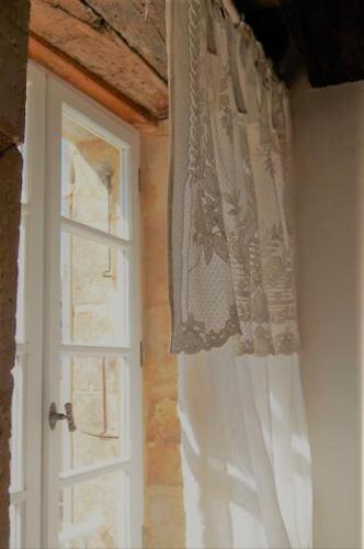 une fenêtre avec un rideau blanc à côté d'une porte dans l'établissement 7 Au Charme d'Antan, à Beaumont-du-Périgord