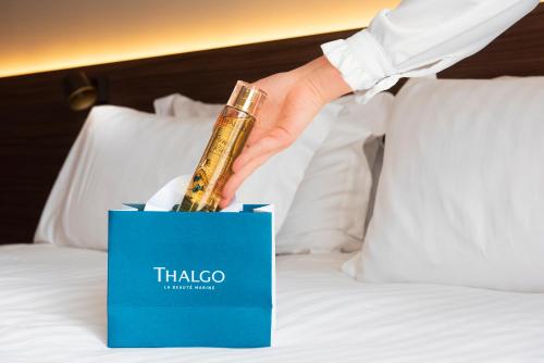 a person holding a bottle in a box on a bed at Radisson Blu Hotel, Rouen Centre in Rouen