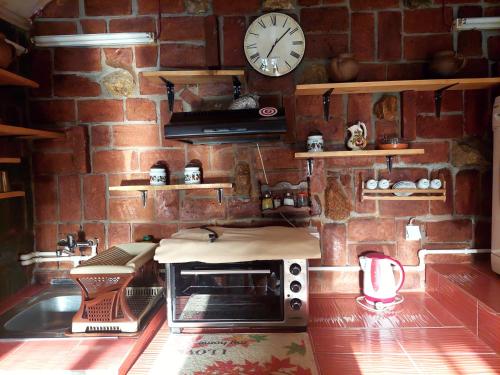 uma cozinha com uma parede de tijolos, um micro-ondas e um relógio. em Apartmani Bogatić em Bogatić
