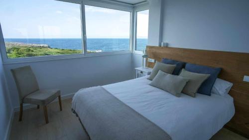 a bedroom with a bed and a window with the ocean at Apartamento Sunset con vistas Playa de Los Locos in Suances